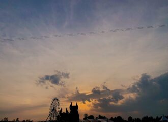 Zu sehen sind die zwei Maskottchen des Highfield Festival vor einem Sonnenuntergang.